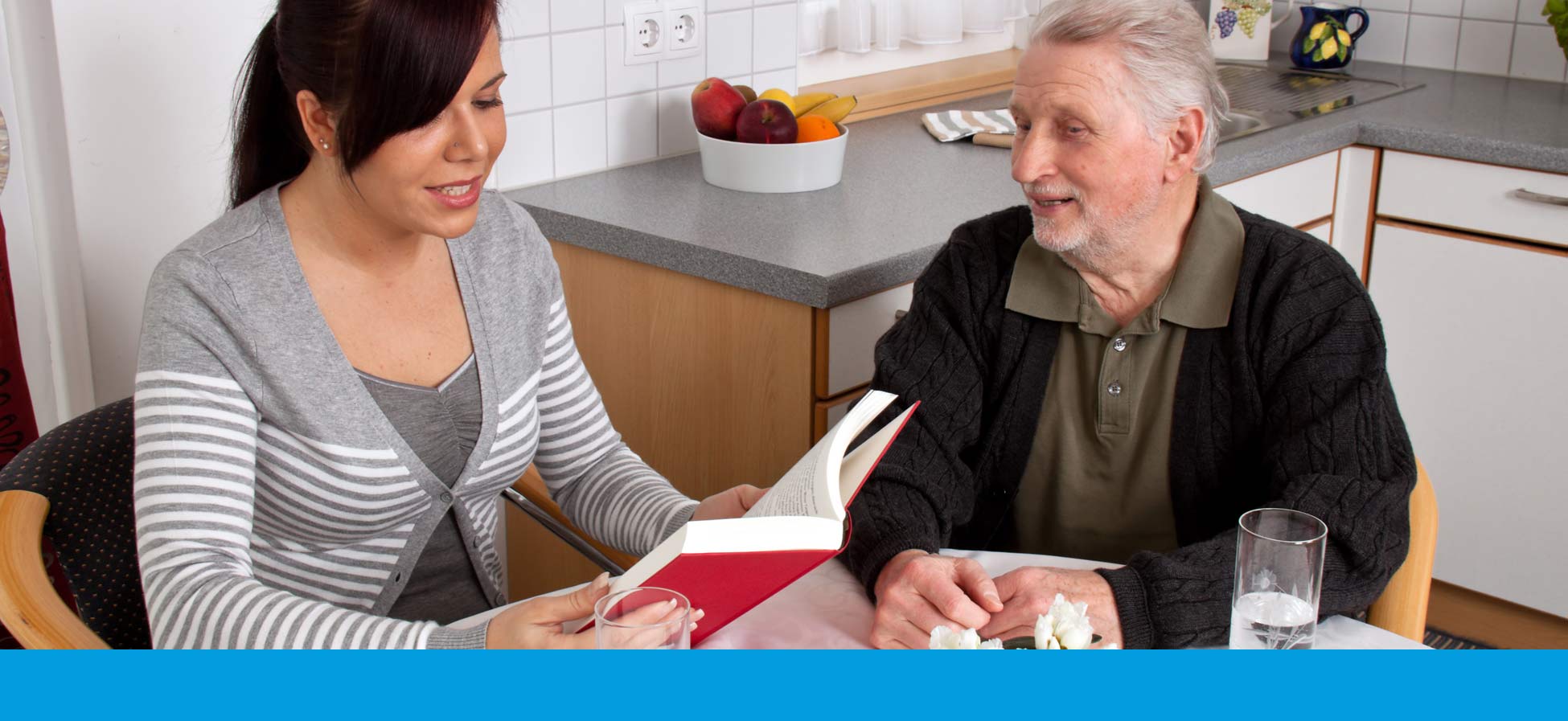 Frau liest alten Mann aus Buch vor